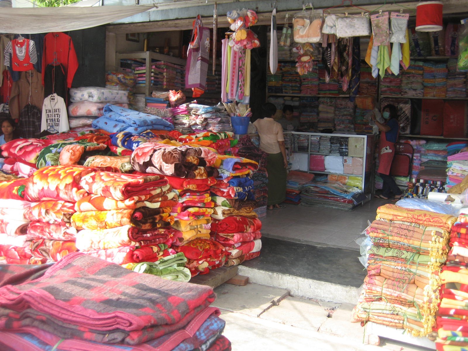 A textile shop in Mandalay stacked with colorful synthetic blankets.