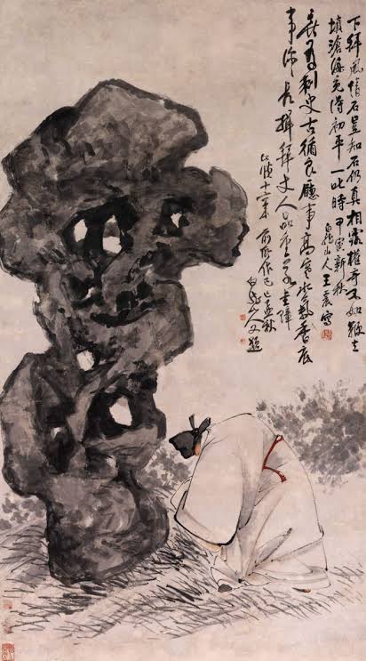 A robed Chinese figure crouches beside a towering scholar’s rock in an ink painting.