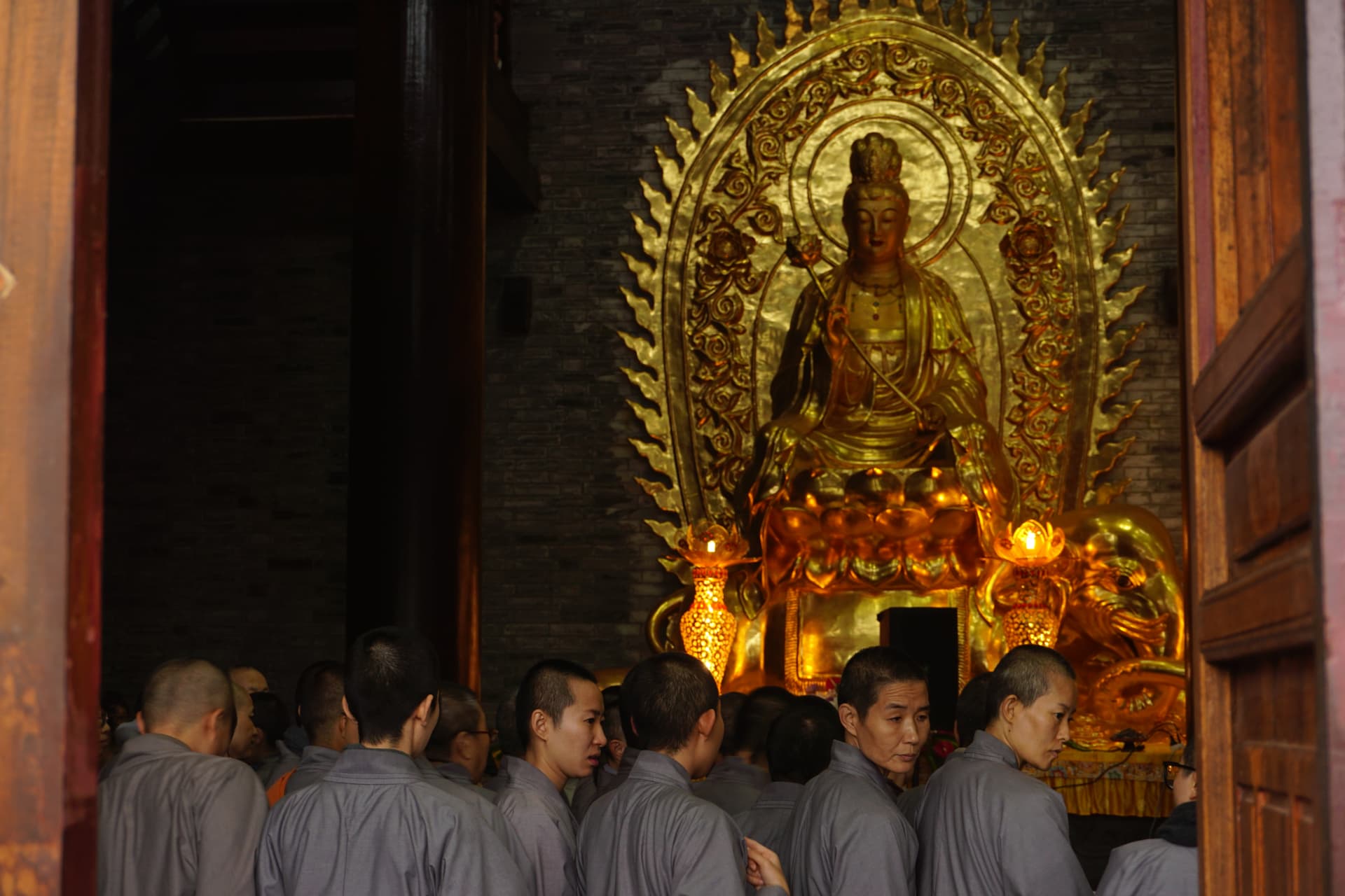 Monastics gathered before a gilded Buddhist figure inside a temple in west China.